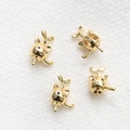 Macro-detail van vier vergulde kattenhoed-hangers voor DIY-sieraden op witte stof - Goud