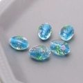 Macro shot of oval blue glass beads with gold foil and purple flower details for DIY jewelry - Ocean Blue
