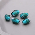 Macro shot of 5 handmade blue-green oval glass beads with floral gold foil for DIY jewelry - Peacock Green