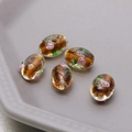 Macro shot of 5 handmade oval amber glass beads with floral gold foil patterns for DIY jewelry - Brown