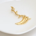 Detailed macro view of a gold-plated scythe-shaped piercing with white zircon inlays - Gold