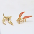 Detailed close-up of gold leaf-shaped components with pink enamel and red crystals - Gold Style