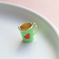 Vista macro di un ciondolo a mini tazza verde smaltata con cuore e bordo dorato - Tazza Verde