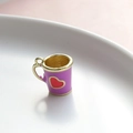 Dettaglio macro del ciondolo a forma di mini tazza viola con cuore rosso e oro - Tazza Viola