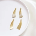 Dettaglio di quattro ciondoli a nappa in lega dorata per gioielli DIY su seta bianca - Pezzo Singolo / Stile Nappina Dorata