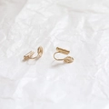 Dettaglio ravvicinato di orecchini a clip a spirale dorati con trama martellata su fondo bianco - 18k Con Tappo Tubo Gomma