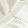 Dettaglio macro della catena a graffetta placcata oro 14k su elegante sfondo di seta - Stile Dorato Ovale Lungo (4#)
