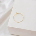 Détail de créoles en or 14k avec texture torsadée sur un support minimaliste - Rond Torsadé (18K)
