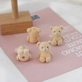 Detail view of mini flocked beige teddy bear charms with DIY holes for accessories - Yellow