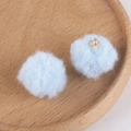 Detail of light blue fluffy pom-pom charms with gold metal loops on a wooden tray - 5# Pale Blue