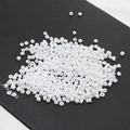 Macro view of 2mm white porcelain seed beads stacked on a black surface for DIY jewelry - 10 g / White