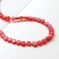 Vue détaillée de perles fleurs en verre rouge disposées en courbe pour bijoux DIY - 1 Pièce (ai-environ 68 perles) / Rouge