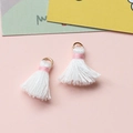 Nahaufnahme der weißen Baumwollquasten mit rosa Faden und goldenen Ringen für DIY-Schmuck - Weiß