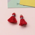 Makroaufnahme roter handgefertigter Baumwollquasten mit Goldringen für DIY-Schmuck - Rot
