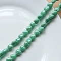 Macro shot of glazed mint green heart-shaped ceramic beads for DIY jewelry making - Green