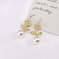 Dettaglio di orecchini floreali con petali di smalto bianco e perle su base dorata - Giallo