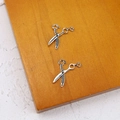 Detailed view of silver scissor-shaped jewelry pendants on an orange wooden surface - Vintage Scissors (8#)