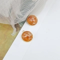 Detailed shot of round gold-trimmed orange resin pendants with dried floral inclusions - Orange