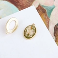 Detailed macro view of vintage oval shell pendant DIY earring accessory with gold bead edging - Light Green