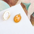 Macro detail of oval gold-plated shell charms and sunburst frames for DIY jewelry making - Light Orange