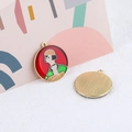 Detail of artistic enamel pendant showing character illustration and golden textured back - Red Round Lady Portrait Style With Bell Hat