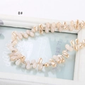 Macro detail of pearlescent teardrop beads in light beige on a decorative white frame - Light Pink