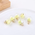 Close-up of spherical glass pendants with dried flowers and gold caps for DIY jewelry making - Light Yellow