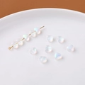 Detailansicht irisierender herzförmiger Glasperlen für DIY-Schmuck auf weißem Tablett - Matt Weiß