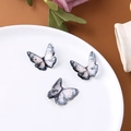 Dettaglio di tre ciondoli a farfalla in resina con sfumatura rosa e accenti in foglia d'oro - Piccolo Nero Grigio (6# Piccola Farfalla)