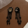 Detailed view of handmade black beaded flower earrings with fringe and gold base - Black