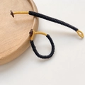 Macro shot of handmade black and gold woven cord with a brown button fastener - Black Gold Style (Size 10 - Price Per Piece)