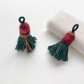 Detail of two handmade dark green tassels with colorful woven tops for DIY accessories - Style 13