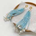 Close-up of light blue beaded tassel earrings with white pearls on a rustic linen background - Single Piece / Blue