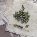 Macro view of vintage olive cylindrical glass beads with white X pattern on linen fabric - 8# Clear Dark Green Cross Bead