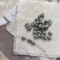 Macro detail of oval Czech glass beads with blue cross pattern and vintage brown accents - 7# Gray with Green Line Cross Bead