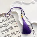 Macro detail of handmade purple silk tassel with colorful beads on a vintage tray - Dark Purple
