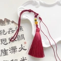 Detail of dark red silk tassel with colorful translucent beads on vintage calligraphy paper - Rose Red