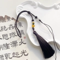 Close-up of handmade silk tassels with tricolor beads and woven knots on white tray - Black