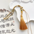 Gros plan d'un gland en soie dorée avec perles sur un fond de calligraphie vintage - Jaune Terre