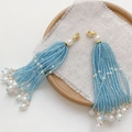 Blue and white beaded tassel charms with gold clasps on a rustic wooden tray - Lobster Clasp Style / Blue