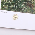 Detail of golden flower charm with dual loops for DIY jewelry making on art book - Eight-petal Flower Double Loop Accessory (14#)
