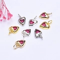 Detailed view of 14K gold and silver heart pendants with red zircon inlay on white fabric - Red Zirconia