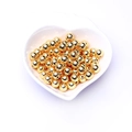 Primer plano de cuentas espaciadoras de oro de 14K en un plato blanco con forma de corazón - 2mm / 18k Oro laminado