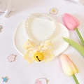 Detail of pet pearl collar with yellow bow and bell on a white decorative plate - Yellow Bell Bow