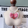 Pink houndstooth bow pet pearl necklace with a red heart pendant on a display model - Red Houndstooth Bow