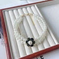 Macro detail of elegant double-row pearl pet necklace with camellia flower and gold lobster clasp - Black (Floral Pattern)