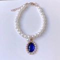 Detail of faux pearl pet necklace featuring a blue gemstone pendant with gold lobster clasp - XS / Blue