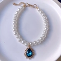 Macro shot of faux pearl pet necklace with water-drop blue gemstone and gold plating - Teal
