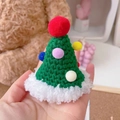Macro shot of hand-knitted green Christmas tree hat with colorful pom-poms for pets - One Size / Christmas Tree Hat