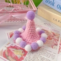 Detailed view of a handmade pink crochet pet party hat with purple pom-poms for cats - One Size / Pink Pompom Hat
